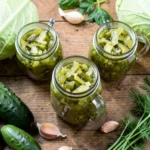 Homemade fermented pickles and sauerkraut in glass jars on kitchen counter